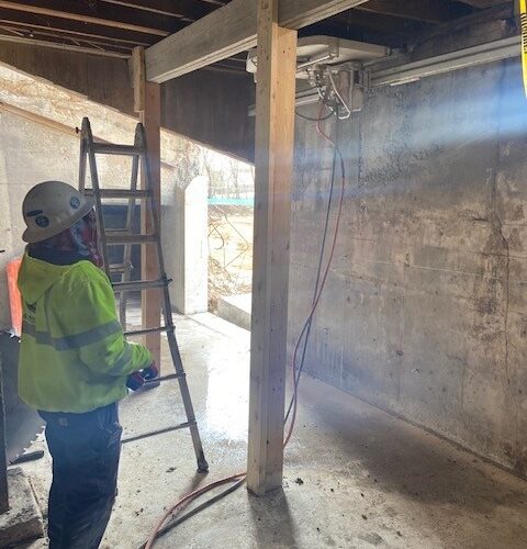 Image of a concrete professional assessing a concrete wall inside a building of a construction site